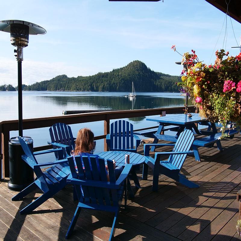 Woman sitting on the deck of Farewell Habour Lodge, looking out over the water.